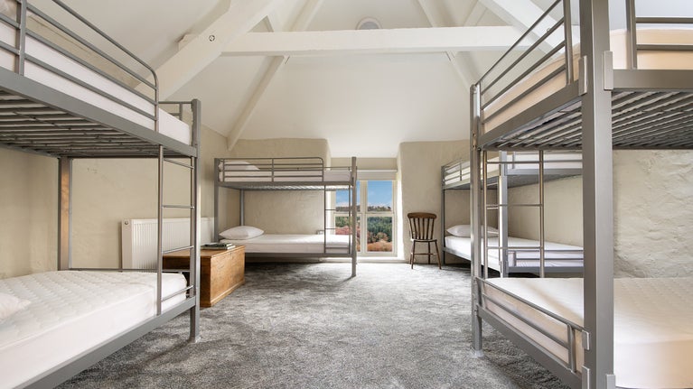 One of the bunkrooms with a vaulted ceiling and four bunkbeds, sleeping eight, at Watkin Bunkhouse, Gwynedd